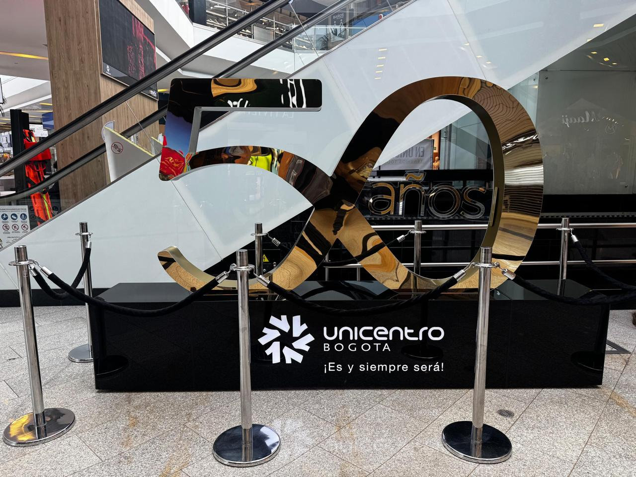 Instalación de los 50 años de Unicentro Bogotá, con superficies metálicas y el identificador del centro comercial.